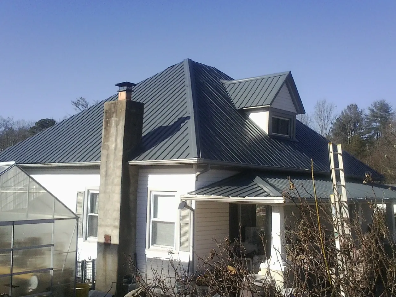 Dark blue standing seam metal roof on a white farmhouse with dormer — Slate & Tile Roof Repair by Roofing Brothers in Hawarden