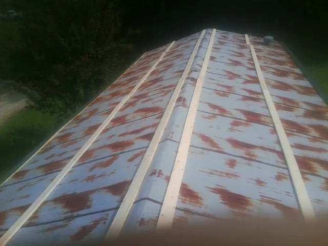 Rusted metal roof panels with new wood purlins before replacement — Storm Damage Roof Repair in Hawarden by Roofing Brothers
