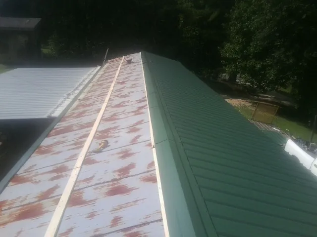 Old rusted panels beside newly installed green metal roofing — Wind Damage Roof Repair by Roofing Brothers in Hawarden