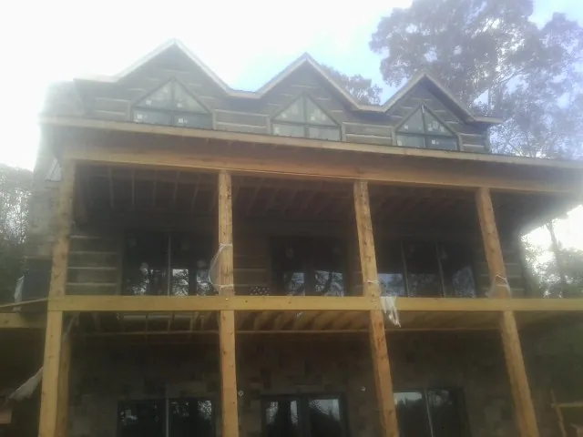Dormers and porch framing on a large log home under construction — Roof Coating work by our crew in Hawarden