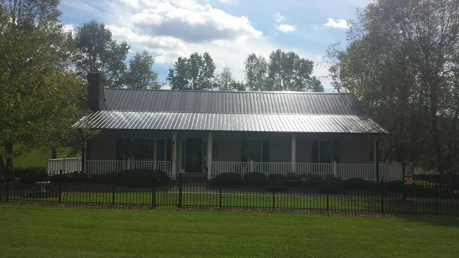 Gray metal roof on a brick ranch with a full width front porch — Gutter Guard Installation work by our crew in Hawarden