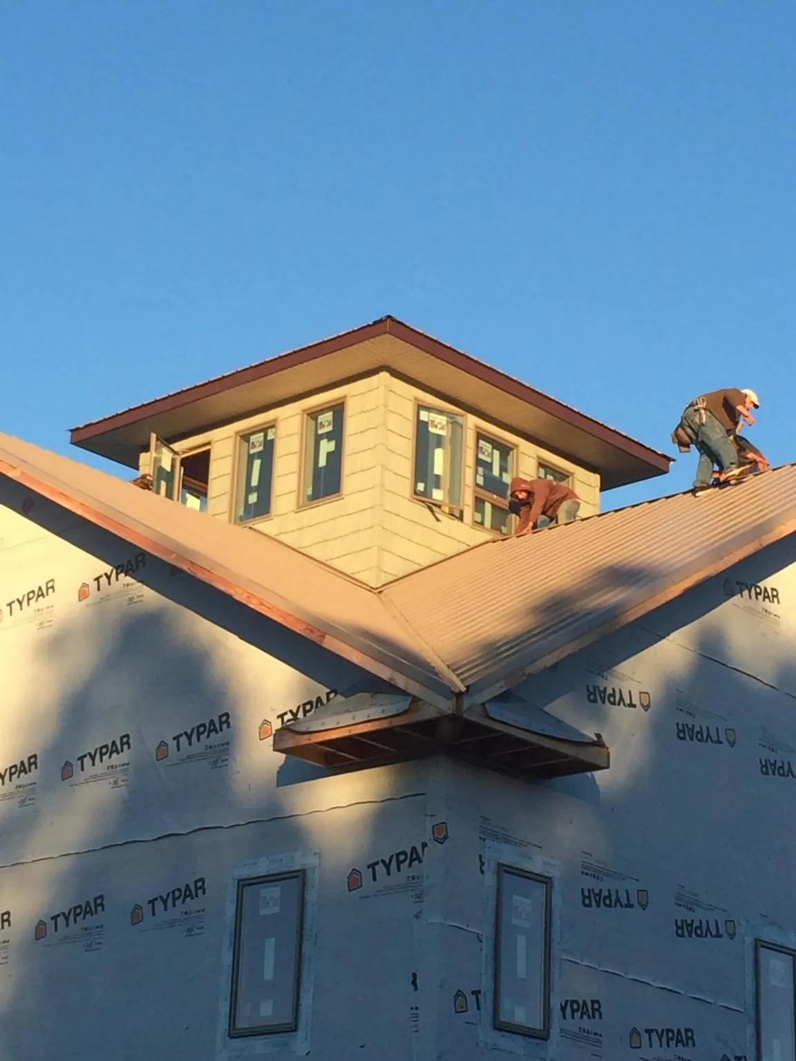 Roofers working around a rooftop cupola on a new metal roof at sunset — Roof Waterproofing in Hawarden by Roofing Brothers